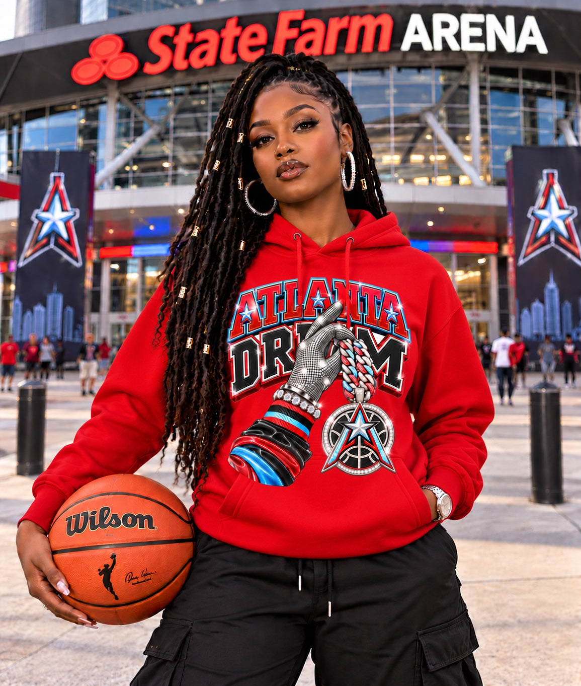 Red Atlanta Dream graphic hoodie modeled by a woman holding a basketball outside State Farm Arena