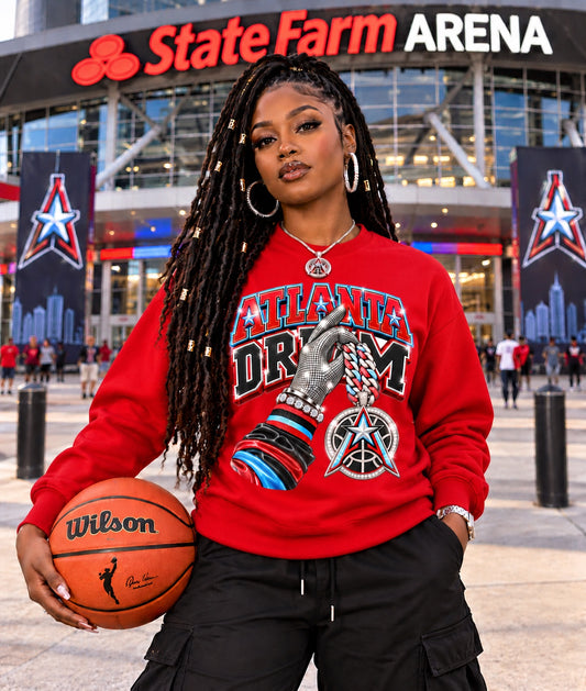 Red Atlanta Dream graphic sweatshirt modeled by a woman holding a basketball outside State Farm Arena